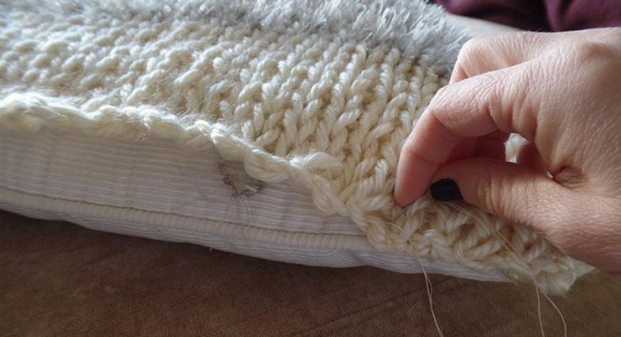 Cosiendo tejido de la funda con aguja e hilo