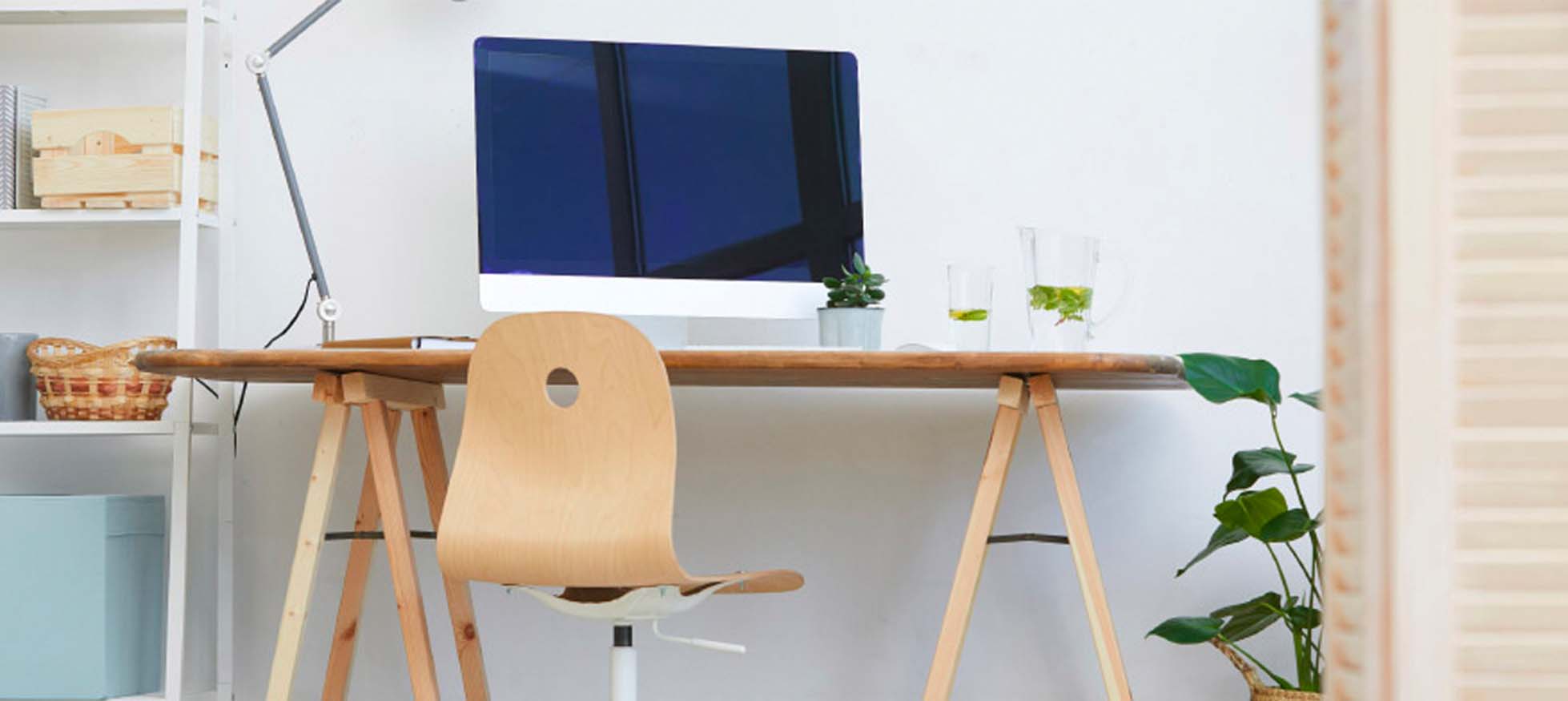 oficina en casa con mesa de madera, silla, computadora, lámpara y plantas