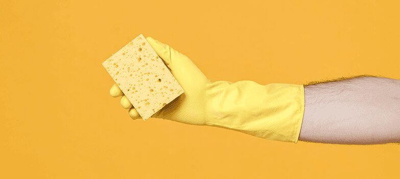 Manos usando guantes y tomando una esponja 