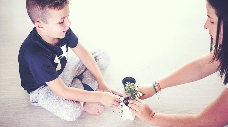 Madre sembrando con su hijo una planta 