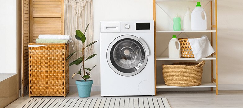 Cuarto de lavado equipado con lavadora, estantes organizados con ropa y envases de productos especiales para suavizar toallas