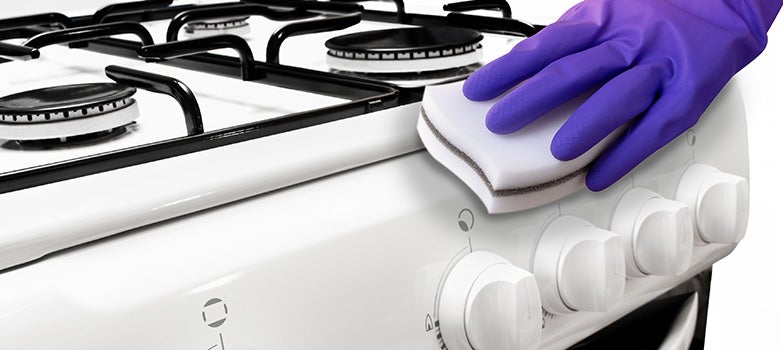 Persona lavando estufa con esponja