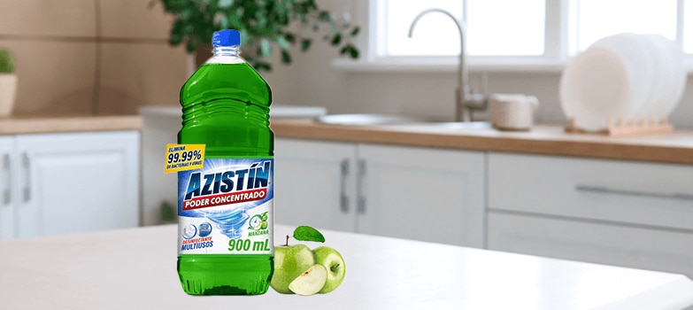 Desinfectante multiusos Azistín con aroma a manzana en primer plano; al fondo, una cocina reluciente.