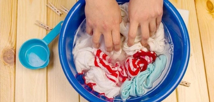 Manos restregando ropa con jabón en un tazón