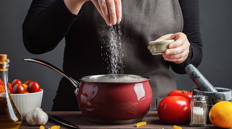 Persona echando sal en una olla