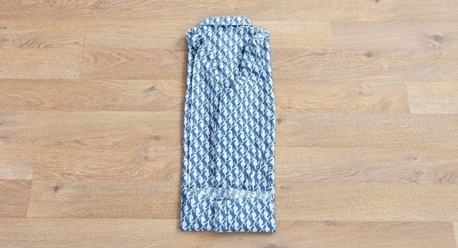 Proceso para doblar una camisa: Acomoda la manga a lo largo del doblez