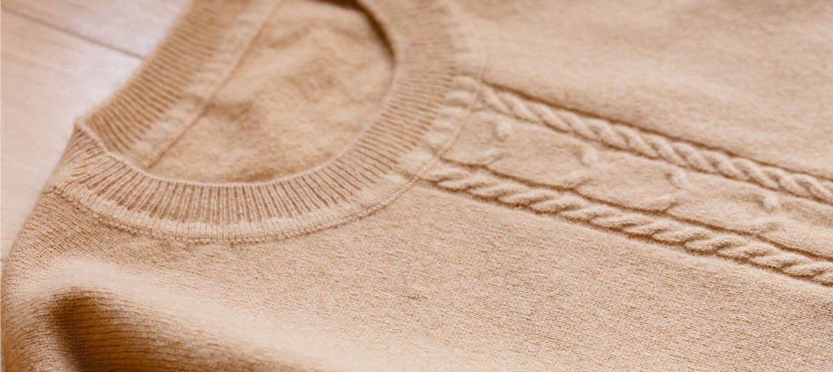 Llena un contenedor con agua fría, sumerge la prenda volteada de adentro hacia afuera. Lava a mano usando un poco de detergente líquido y sécala en una superficie plana