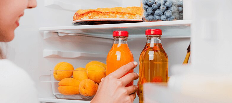 Mujer colocando alimentos en el refrigerador tras una limpieza profunda.