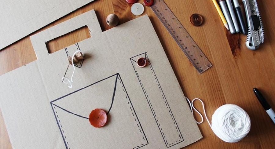 Cartón con forma de portafolio con dibujos de marcador y botones pegados.