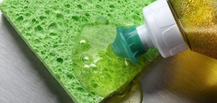 Botella de jabón liquido esparciendo jabón sobre una esponja