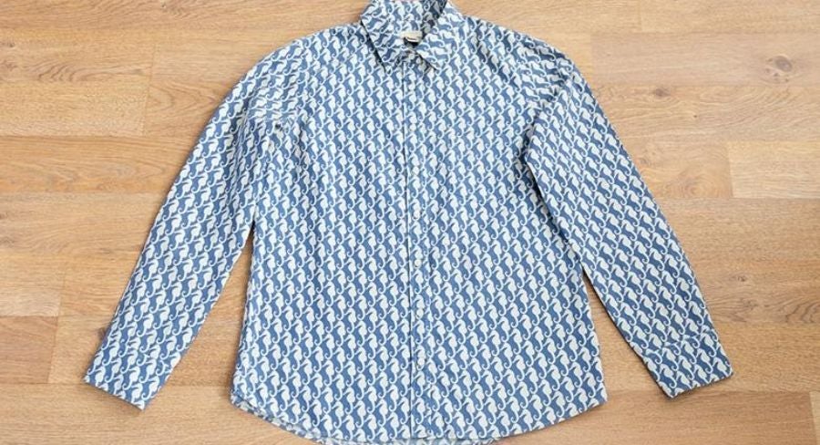 Proceso para doblar una camisa: Abotona la camisa, incluyendo mangas.