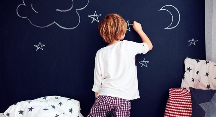 Niño dibujando en una pared de pizarra
