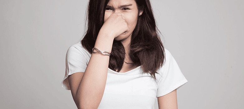 Mujer tapándose la nariz por mal olor causado por el sudor de las axilas