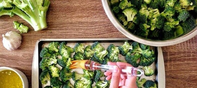 Untando brocolis con aceite en una charola