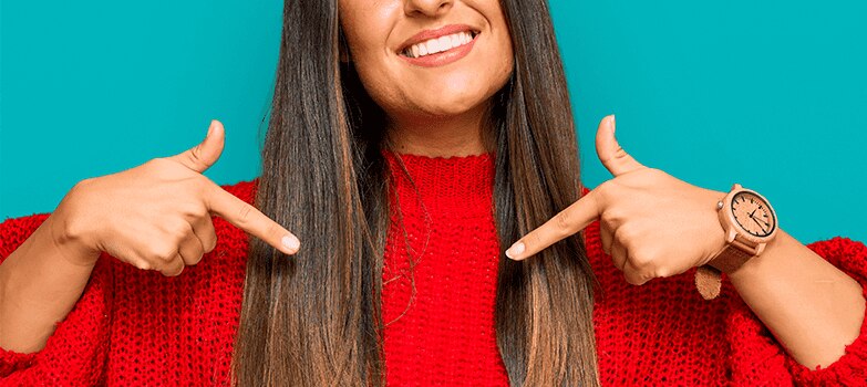 Mujer vistiendo un saco rojo, al que ha aplicado cuidados para la ropa especiales para prolongar su vida útil y mantener la intensidad de sus colores. 