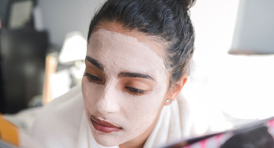 mujer con mascarilla facial leyendo una revista