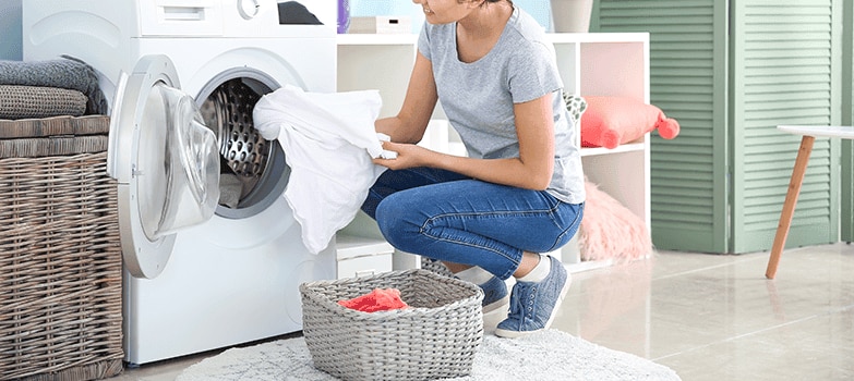 Mujer metiendo ropa en la lavadora