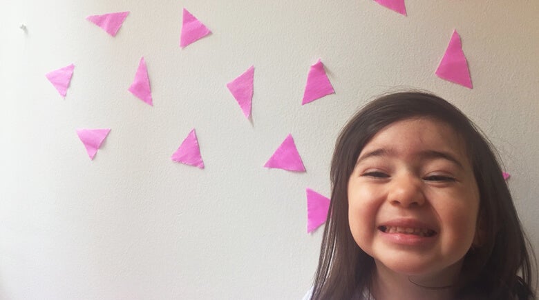 Niña sonriendo en una pared decorada