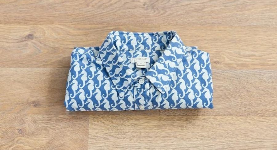 Proceso para doblar una camisa: Haz un doblez al mismo nivel que los puños de las mangas