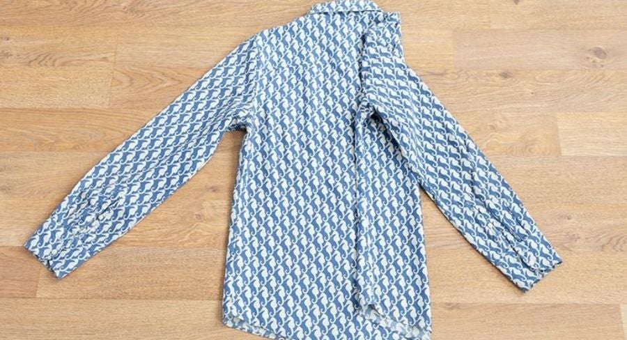 Proceso para doblar una camisa: Voltea la camisa y dobla a la mitad