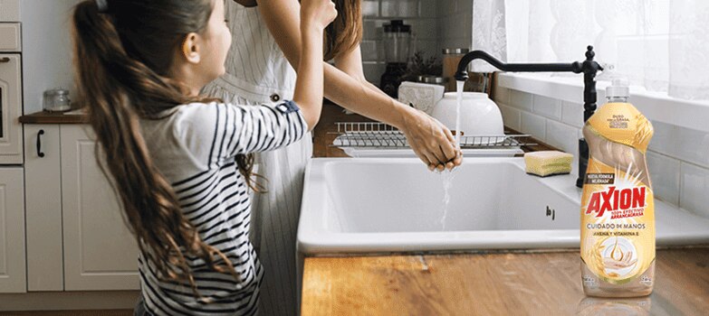 Madre e hija cerca al lavaplatos, con el lavatrastes líquido Axion 