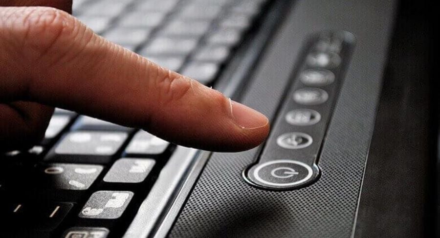 Dedo apagando laptop del botón de encendido